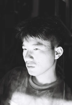 Subtle black-and-white portrait of Paulo Muhongo immersed in deep thought while writing.