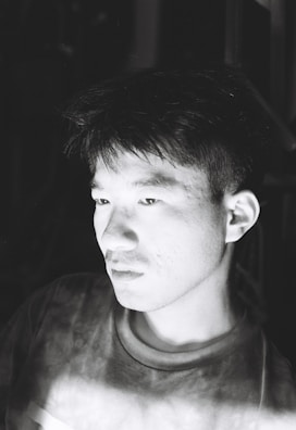 A serene black and white portrait of a person lost in thought, capturing a quiet moment.