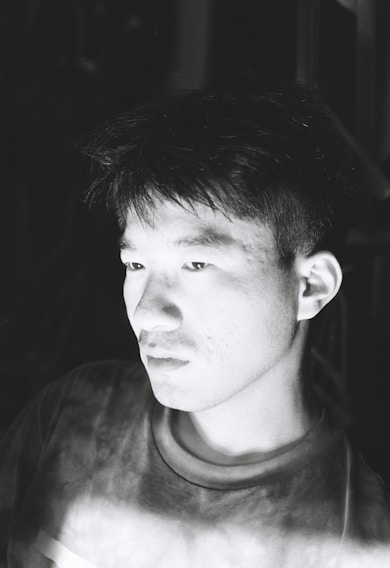 A striking black-and-white portrait of a person caught in a moment of deep thought, showcasing Sami Ur Rahman's skill with light and shadow.