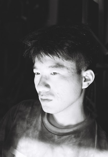 A candid black-and-white portrait of a person lost in thought, highlighting emotion through soft lighting.