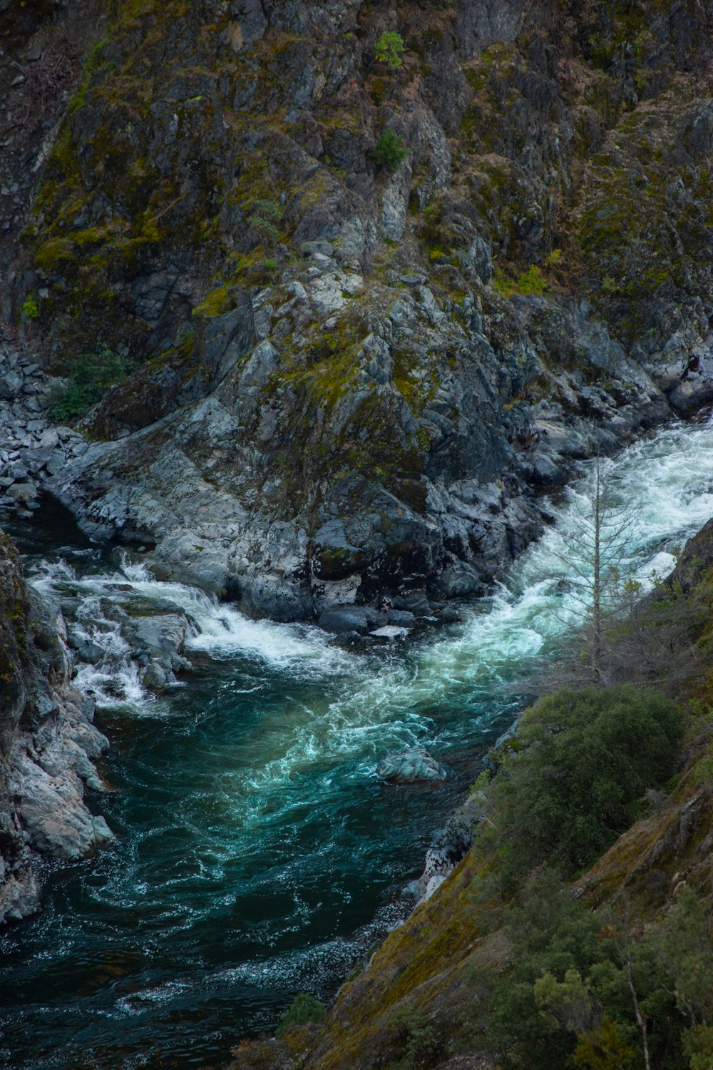 a man standing on the side of a mountain next to a river