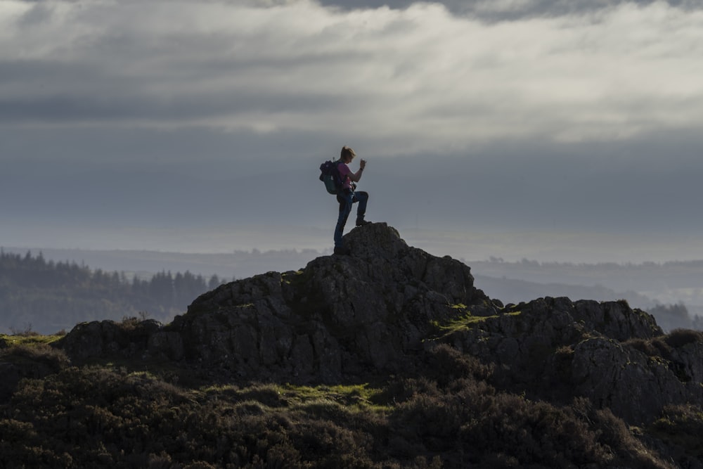 une personne debout au sommet d’une montagne avec un sac à dos