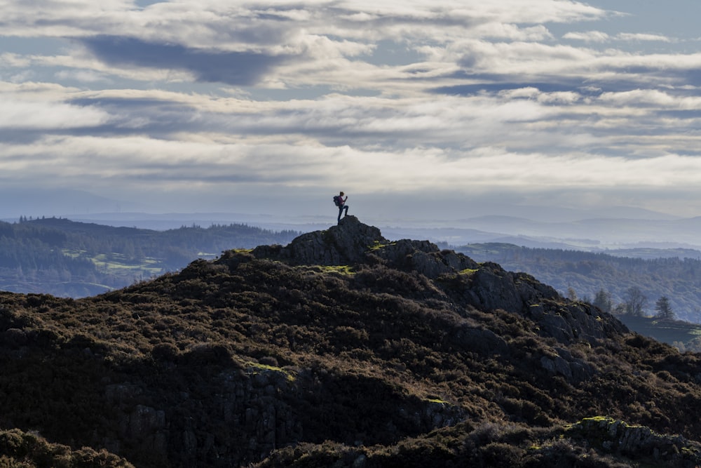 una persona in piedi sulla cima di una collina