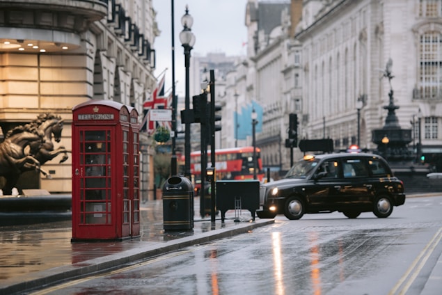 a car driving down a street next to a red phone booth