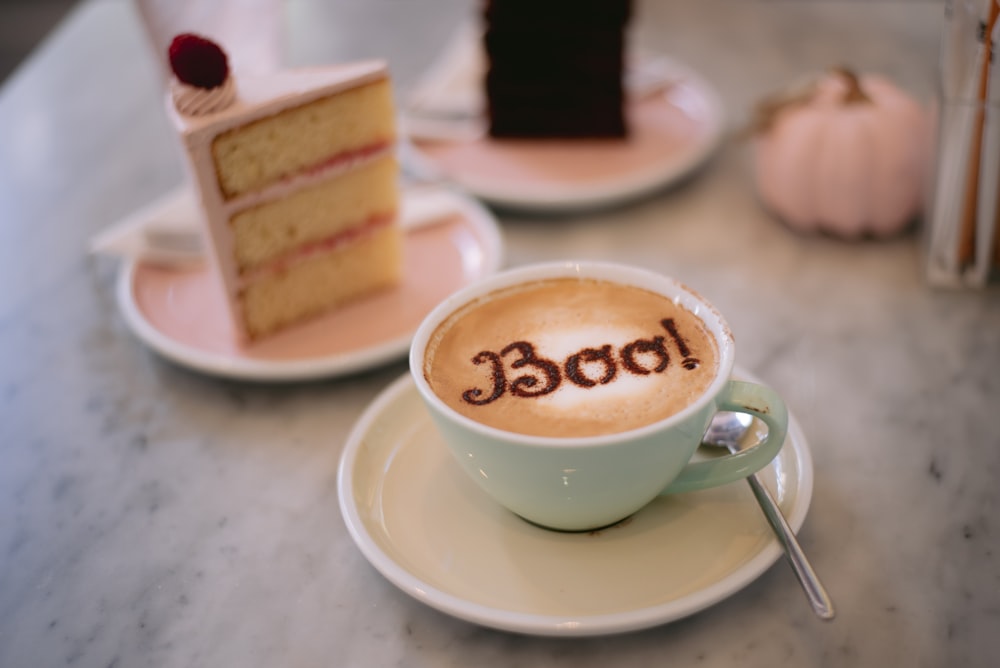 a cup of coffee with a piece of cake in the background