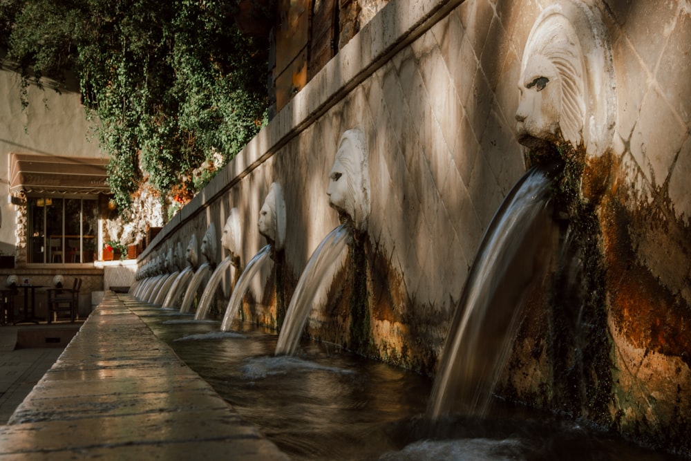 a row of water fountains next to a building