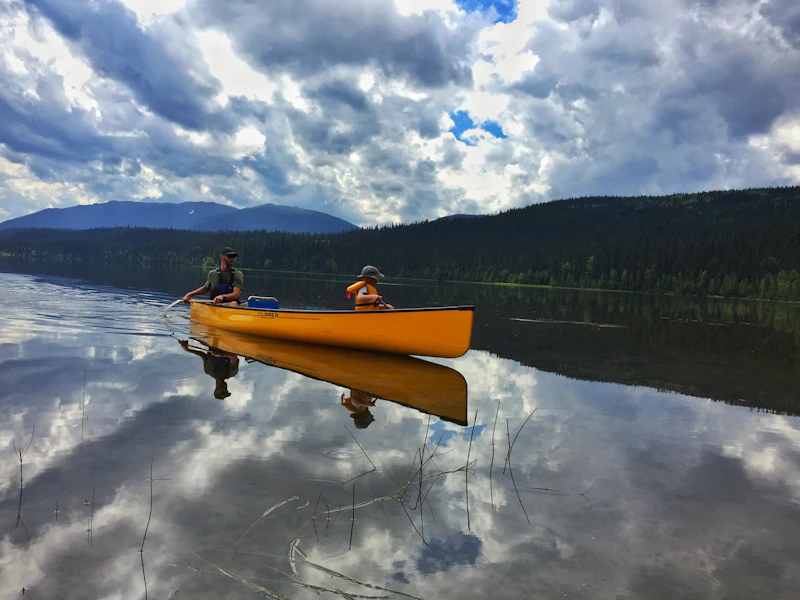 Campers paddling a canoe across the calm camp lake