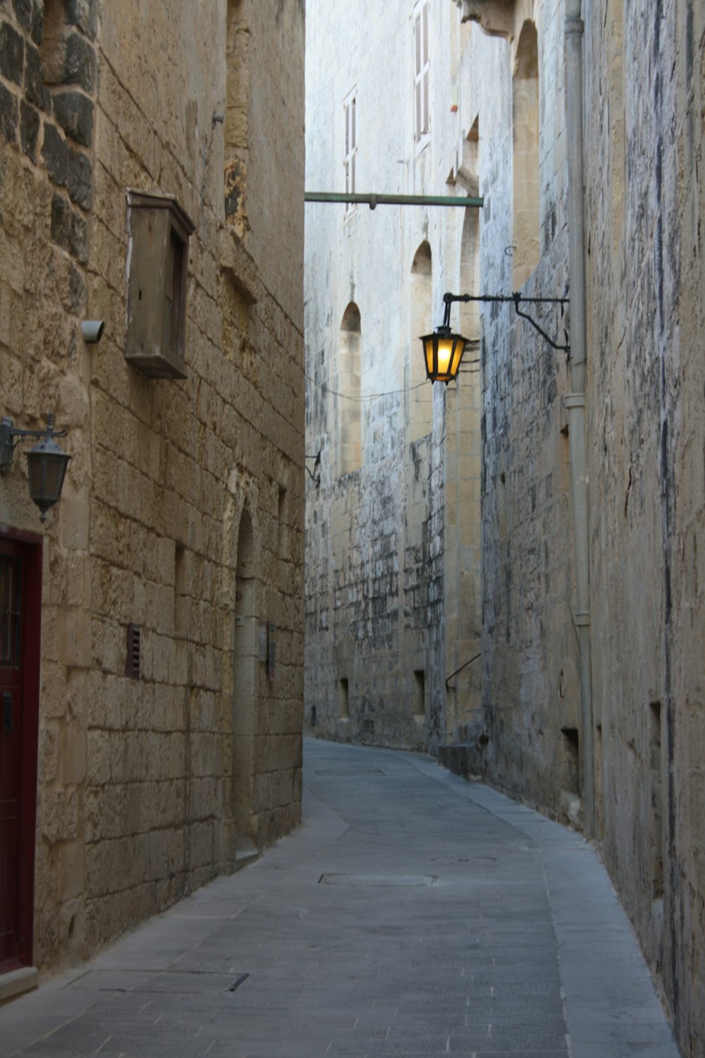 a narrow alley way with a lamp on the side