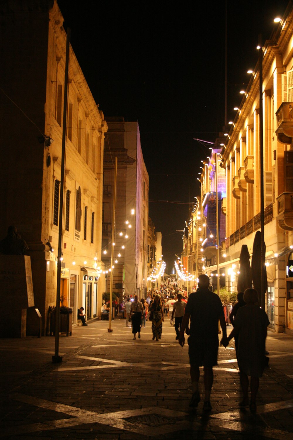 a group of people walking down a street at night