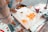 A person is crafting intricate designs using melted sugar on a flat surface, likely at a street food stall. The designs resemble animals and flowers and are being created with a spoon and sticks.