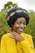 A joyful customer wearing a vibrant handmade headband, smiling in a sunlit garden.