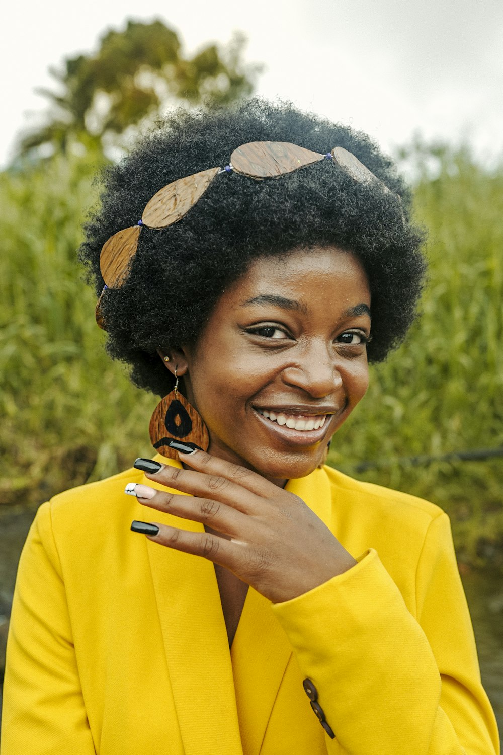 a woman wearing a yellow jacket and a pair of earrings