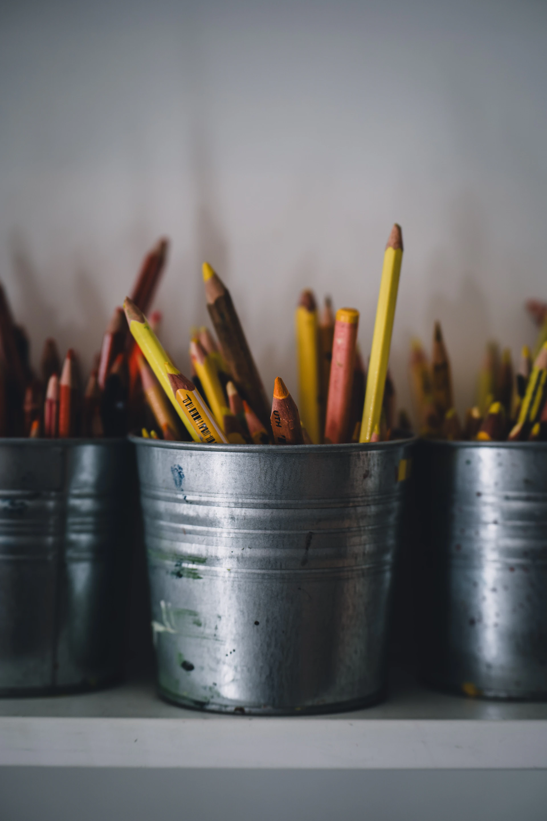 a group of metal buckets filled with pencils