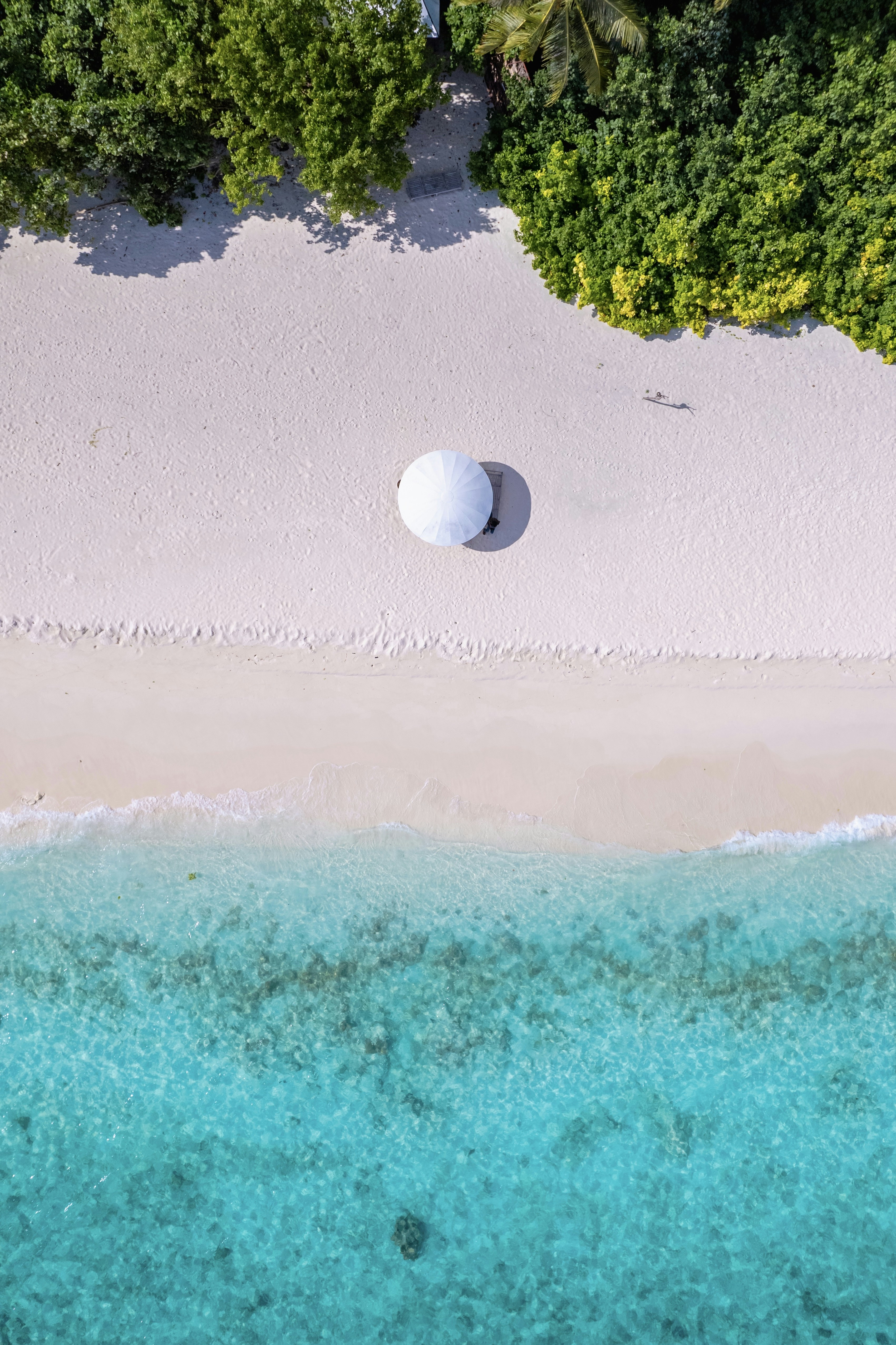 an aerial view of a beach with a white umbrella