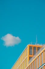 Close-up of a modular container home with clean lines and bright yellow-orange accents under a clear sky.