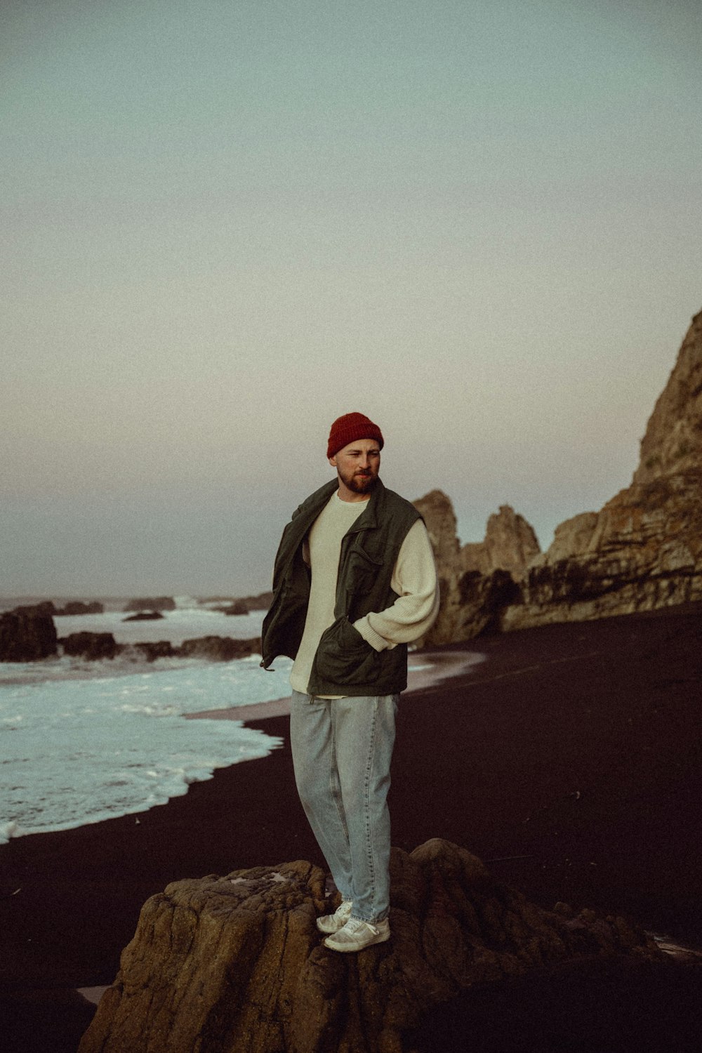 a man standing on top of a rock near the ocean