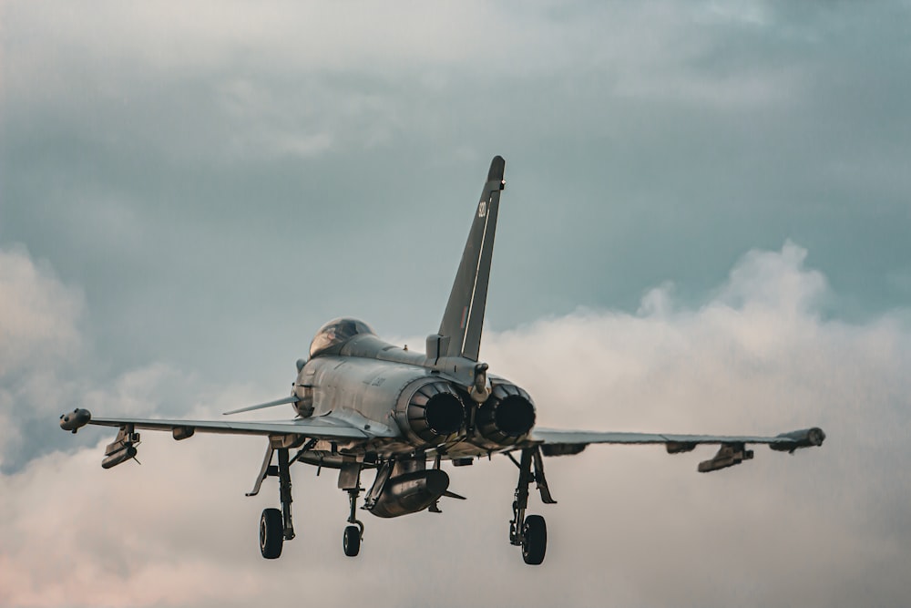 a fighter jet flying through a cloudy sky