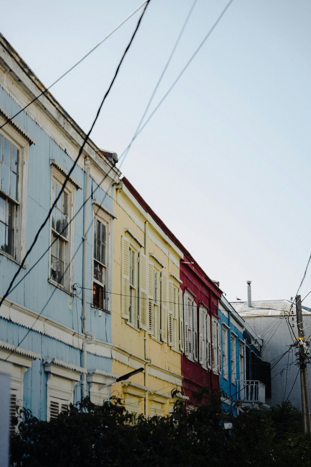 a row of multi - colored houses with power lines in the foreground