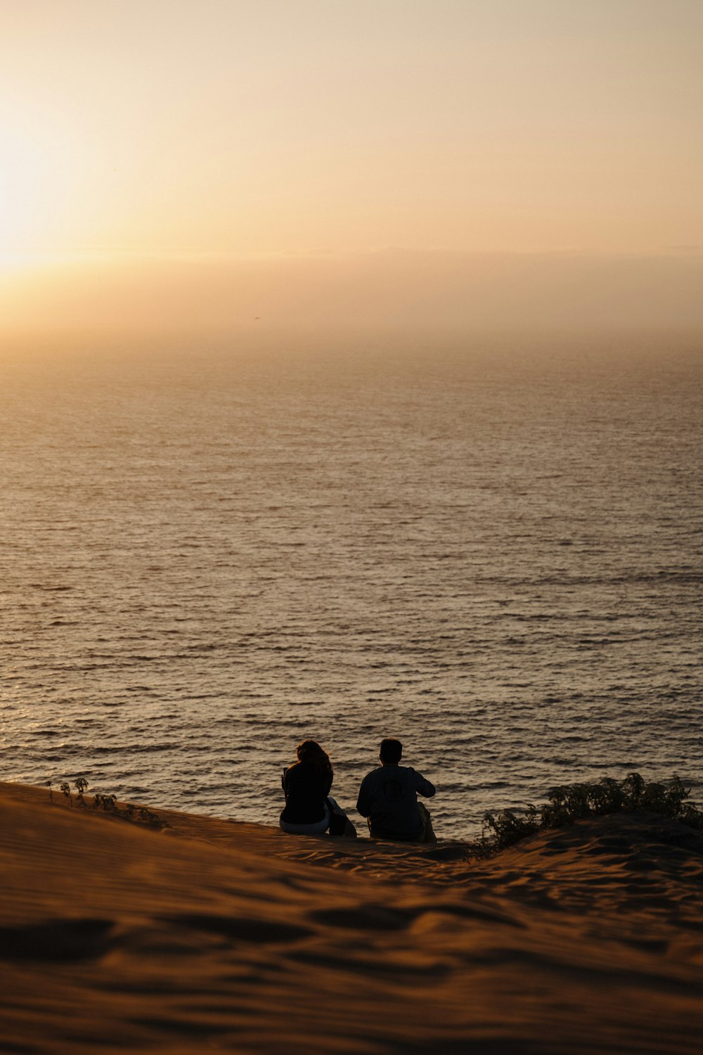 a couple of people sitting on top of a sandy beach