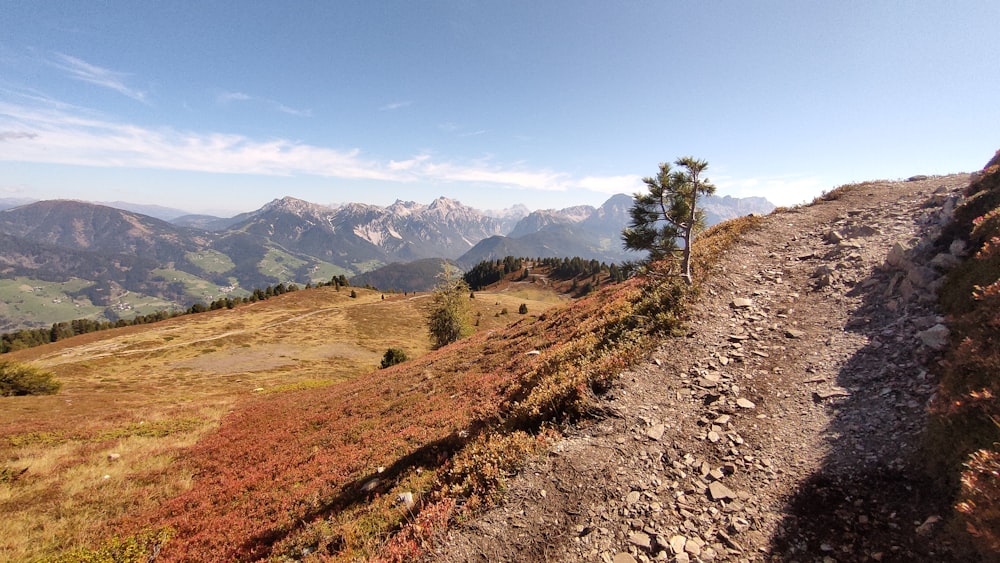 a dirt path going up a hill with mountains in the background