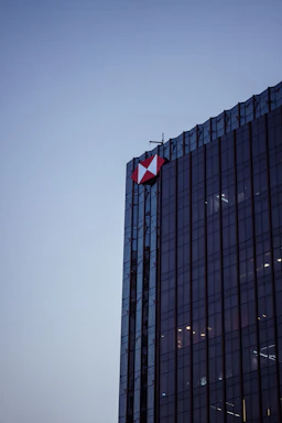 A sleek modern office building with a glowing diamond-shaped logo at dusk.