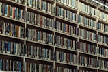 A large library wall with endless rows of books neatly lined up on tall shelves, showcasing a wide collection of books with various colored spines.