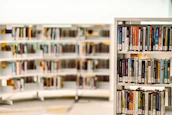 Bookshelves filled with specialized and imported educational books in a bright library.