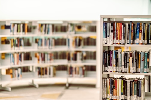 Smiling volunteers organizing books on shelves in a light blue and green themed library.