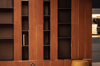 a wooden bookcase with a yellow stool in front of it