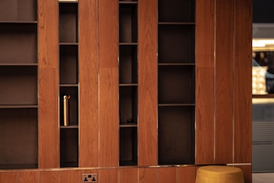a wooden bookcase with a yellow stool in front of it