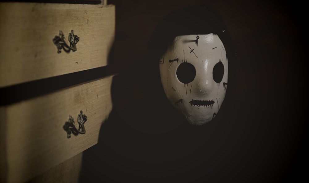 a scary mask sitting on top of a chest of drawers