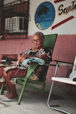 a woman sitting in a green chair in front of a building