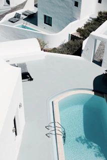 The inviting pool area framed by natural stone and gentle charcoal tones under a clear blue sky.