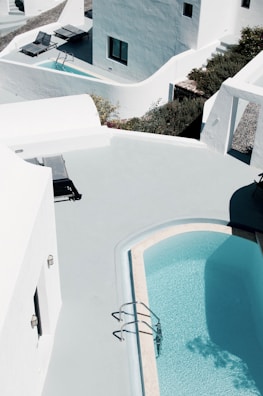 A serene private swimming pool surrounded by modern white walls and soft blue accents.