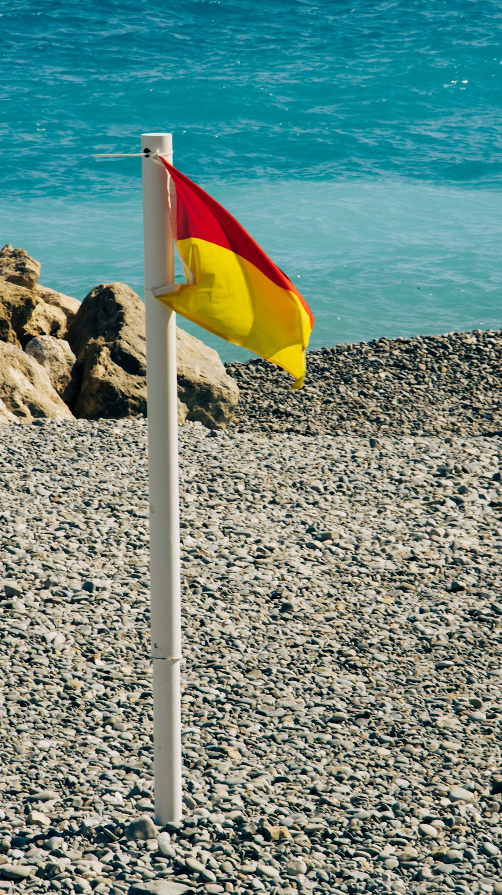 a flag on a pole on a rocky beach