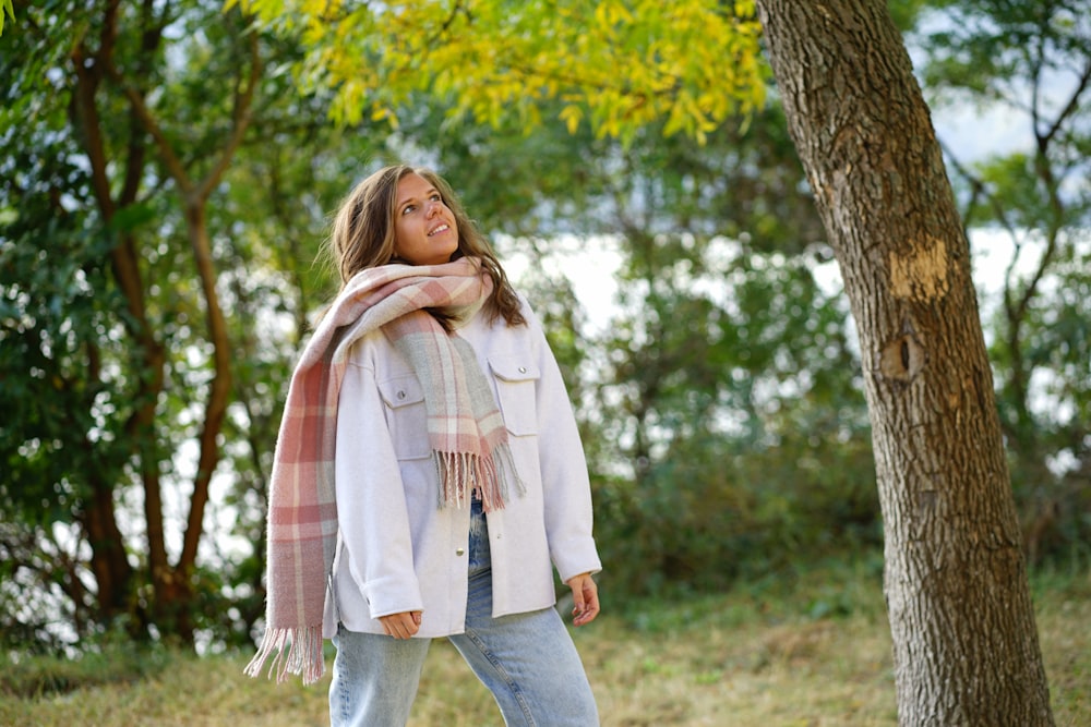a woman standing in the woods with a scarf around her neck