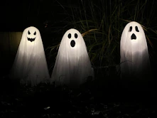 three ghost statues in the dark with their faces glowing