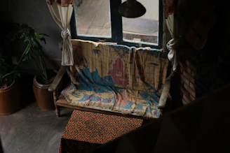 A cozy boho wall tapestry hanging above a rustic wooden bench with soft cushions.
