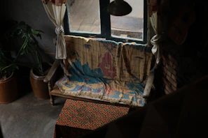 A cozy boho wall tapestry hanging above a rustic wooden bench with soft cushions.