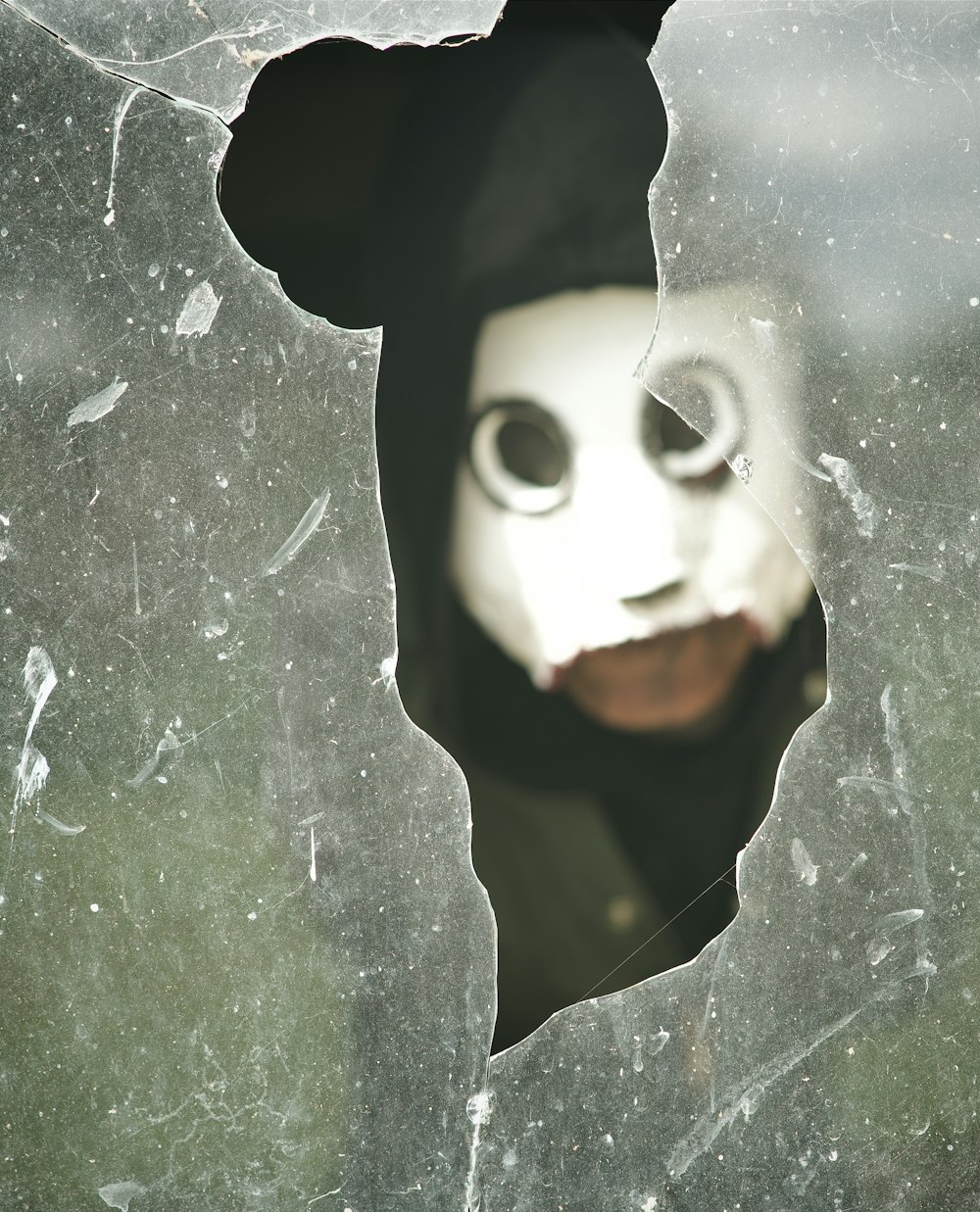 a person wearing a mask through a broken window