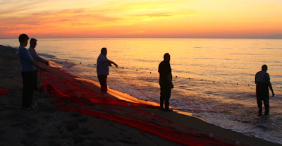 A group of local fishermen sharing stories and laughter by the shore at sunset