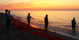 A group of local fishermen sharing stories and laughter by the shore at sunset