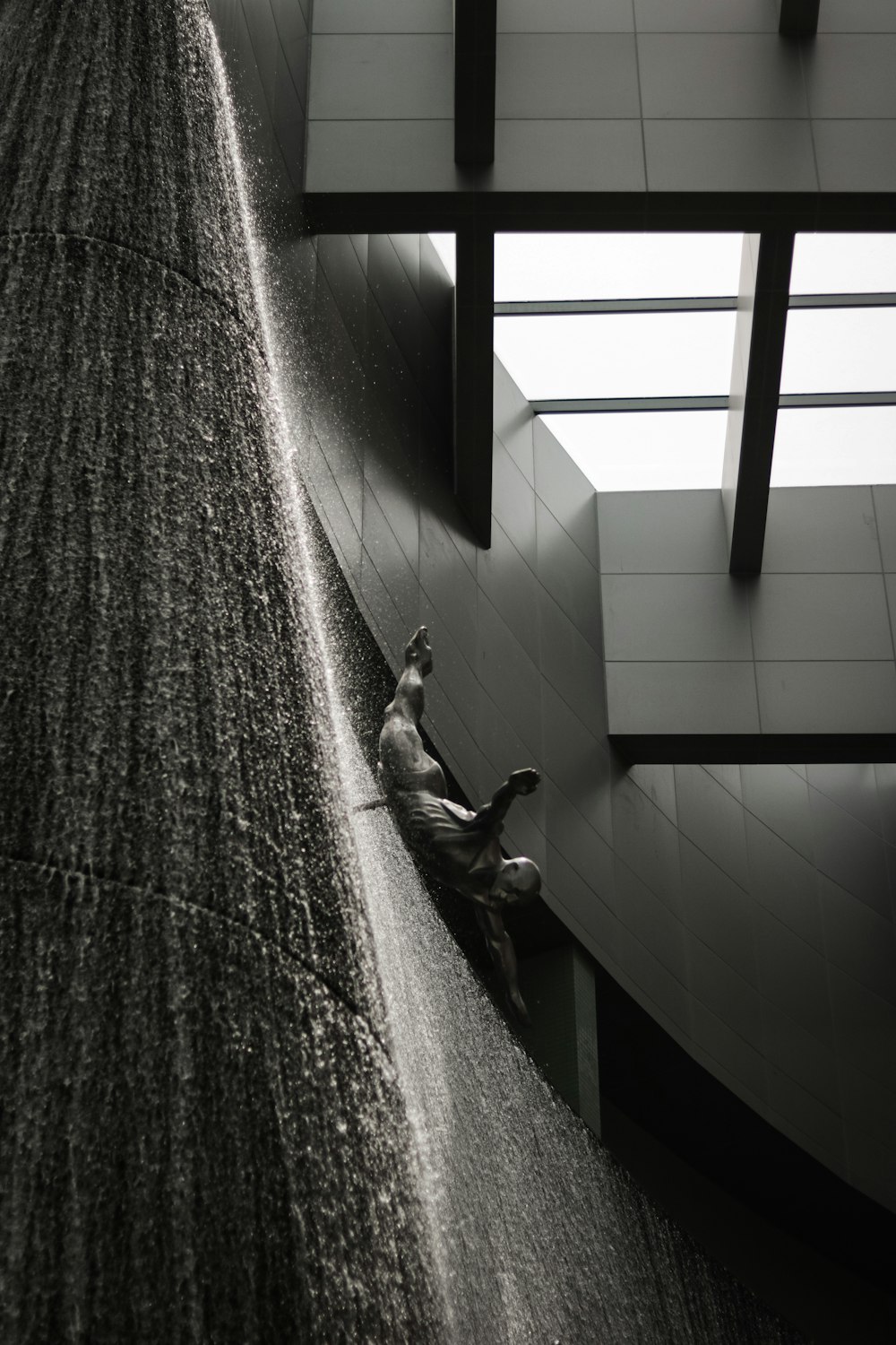 a man sitting on the side of a building next to a waterfall