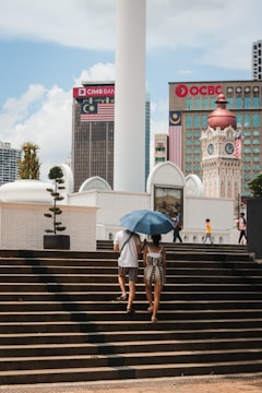 two people walking up some steps with an umbrella