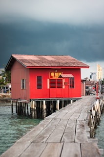 a red house sitting on top of a wooden pier