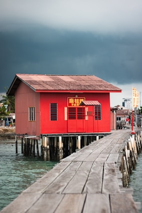 a red house sitting on top of a wooden pier