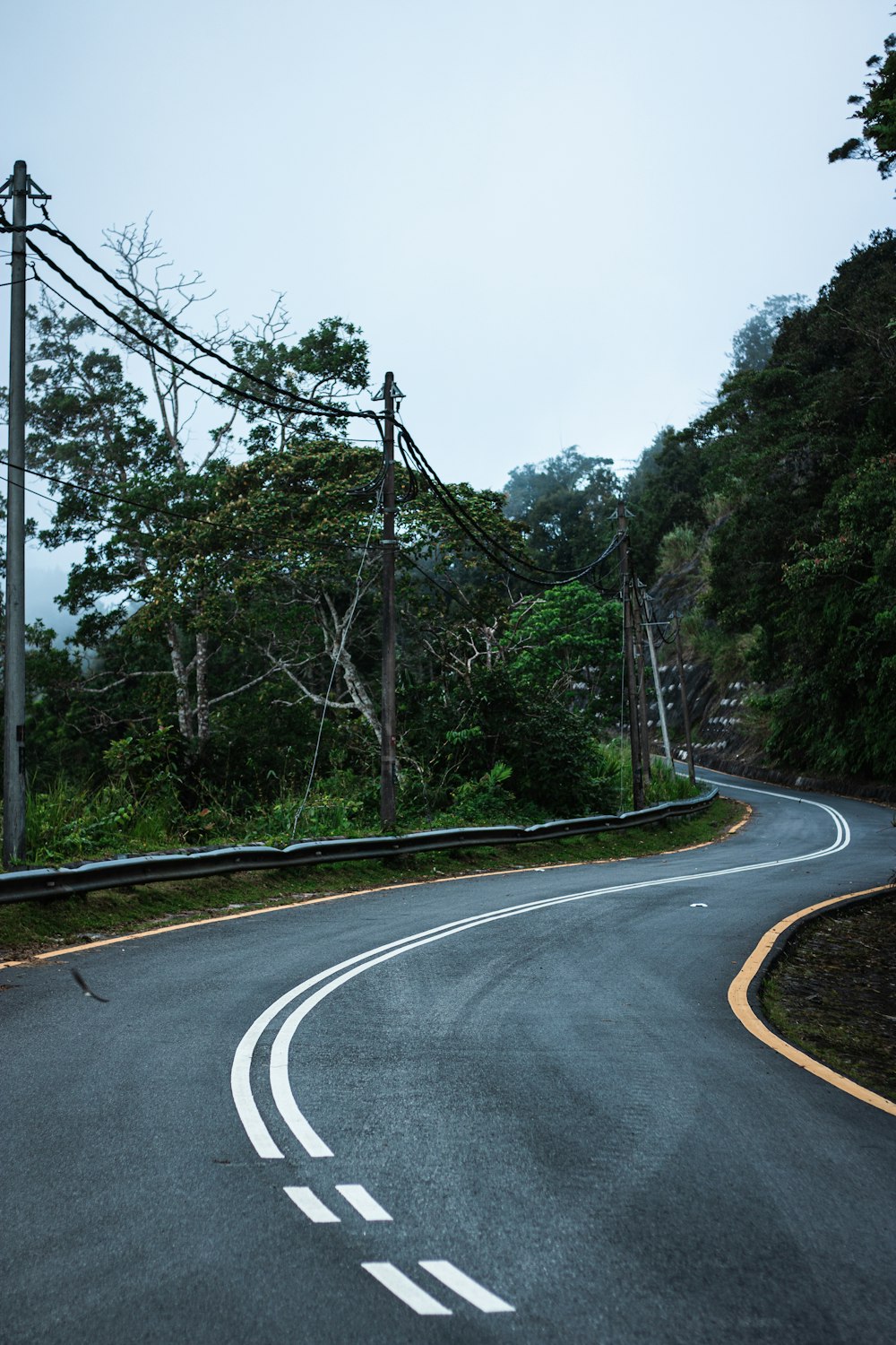 a curve in the road with power lines above it