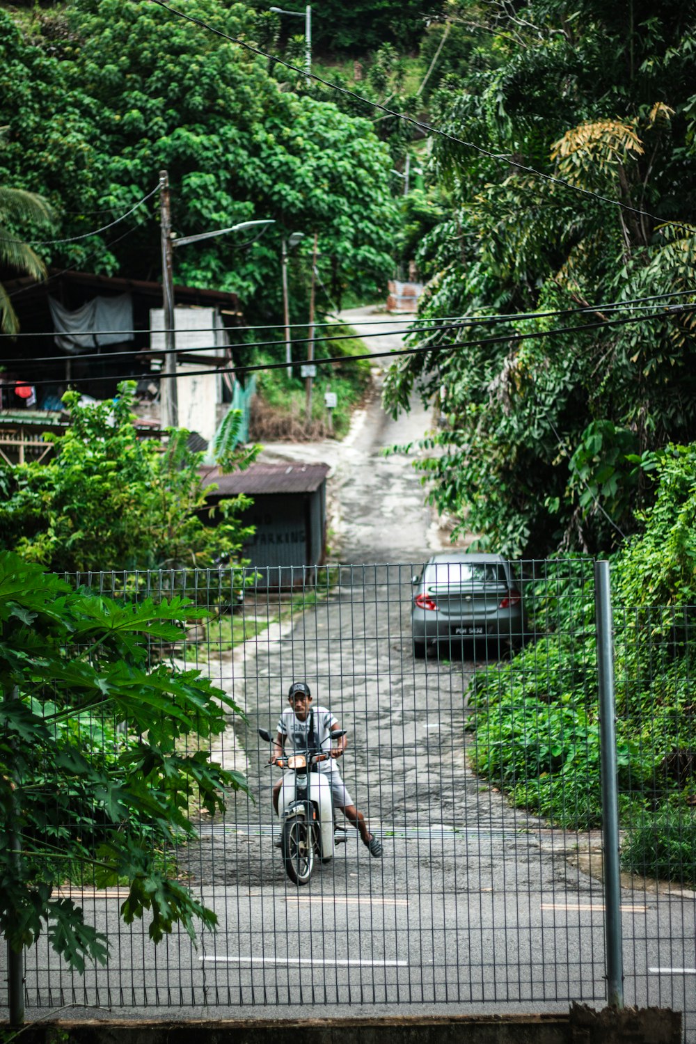 a man riding a motorcycle down a road next to a forest