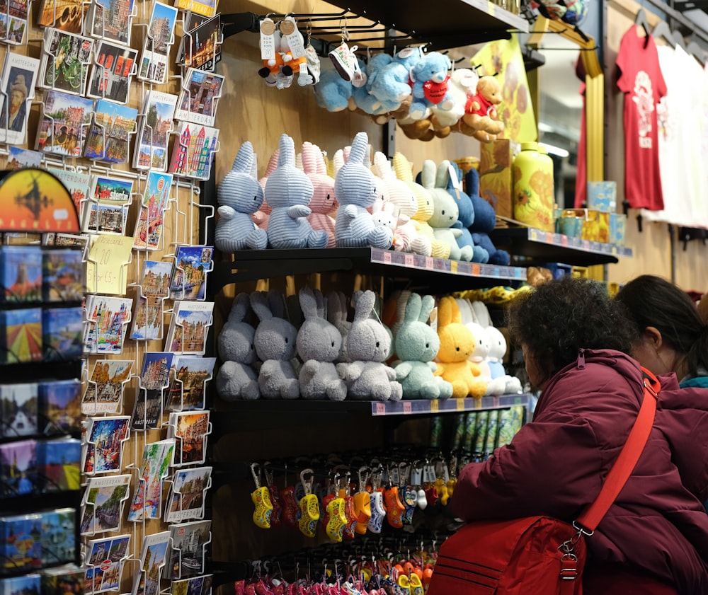 a woman standing in front of a store filled with stuffed animals