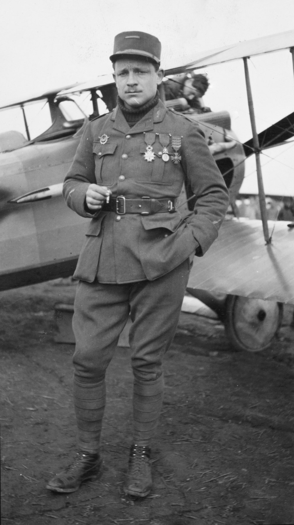 Teniente Raoul Lufbery, retrato de cuerpo entero, de pie junto al avión, en uniforme, mirando ligeramente a la izquierda.